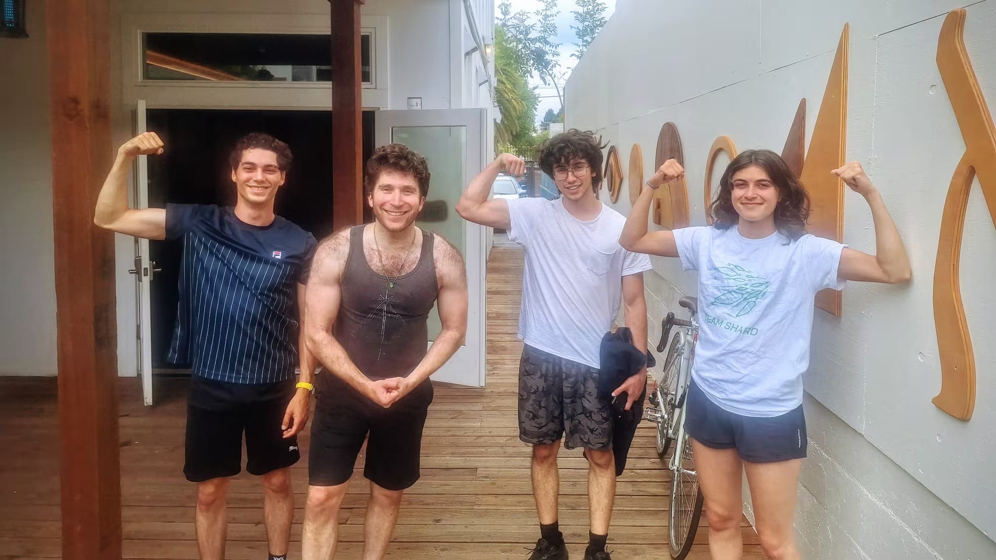 Four smiling people flexing for the camera.
