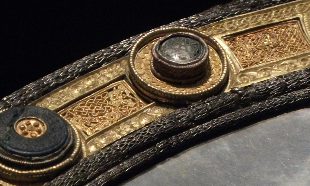 Photo of an ornate silver plate with gold decorations. There are silver knit wire tubes around the edge.