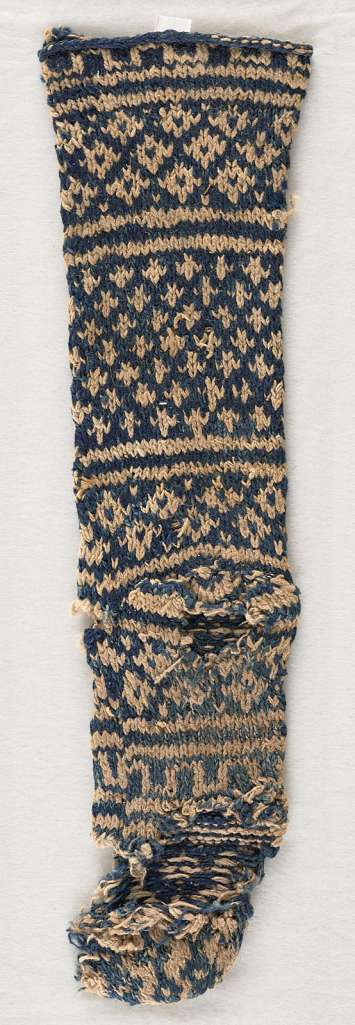 Photo of an old tattered blue and white sock with geometric designs.