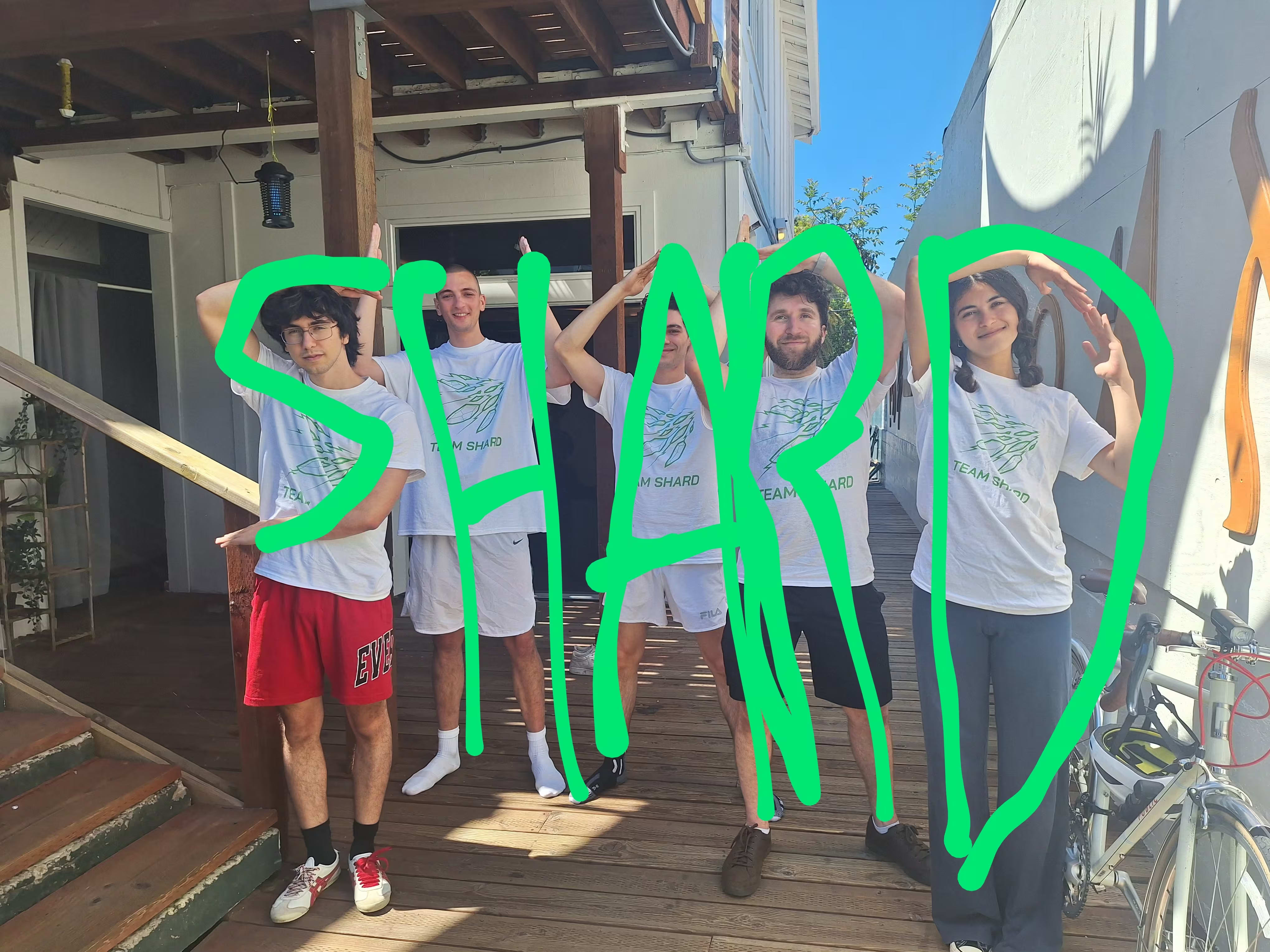 Five people outside of a gym loosely spell "S H A R D" with their poses, with green lettering drawn over each person.
