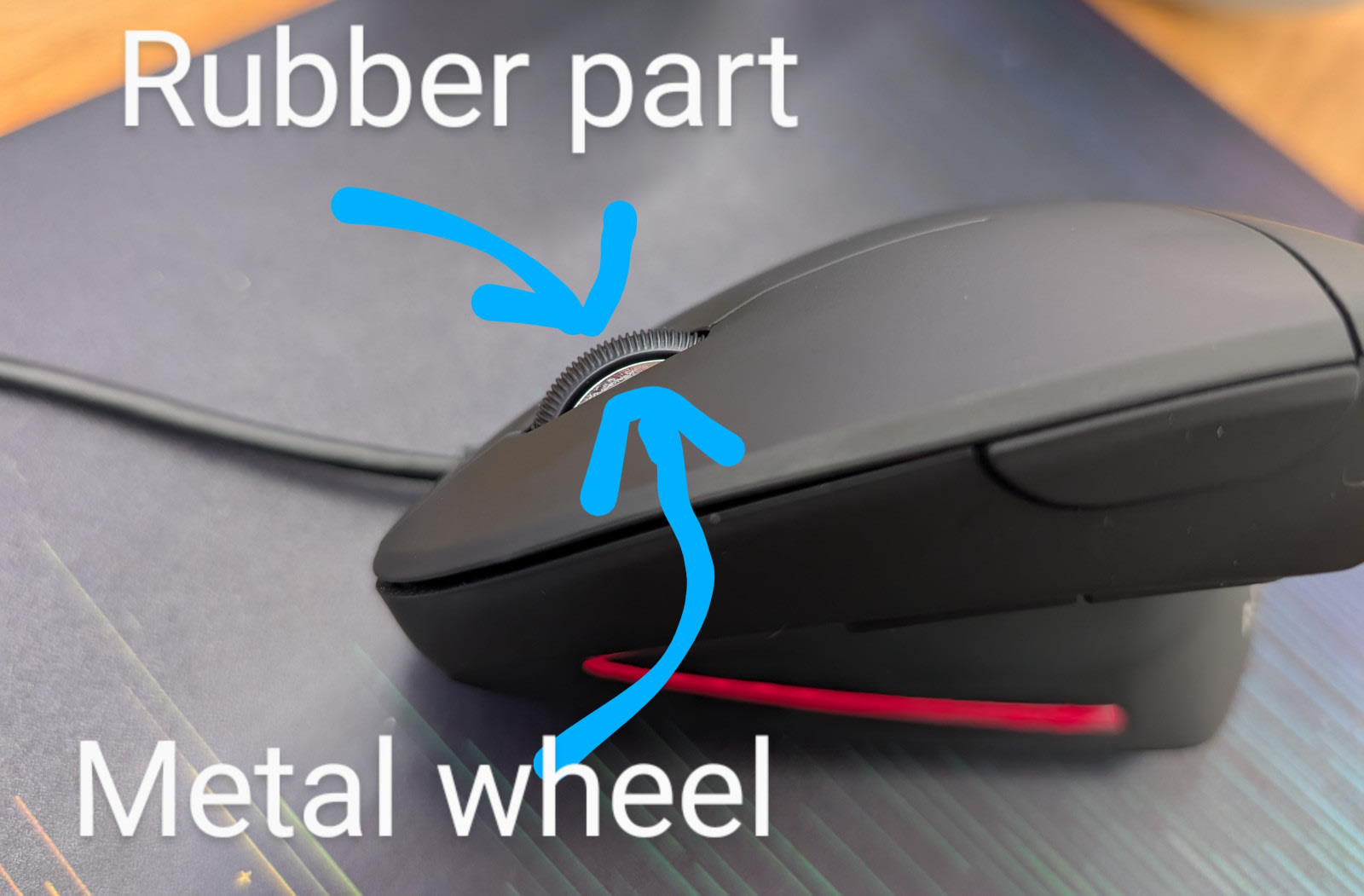 Imagine pointing out the rubber part and wheel part on the mouse. The rubber part is textured and surrounds the metal wheel which is recessed into the mouse.